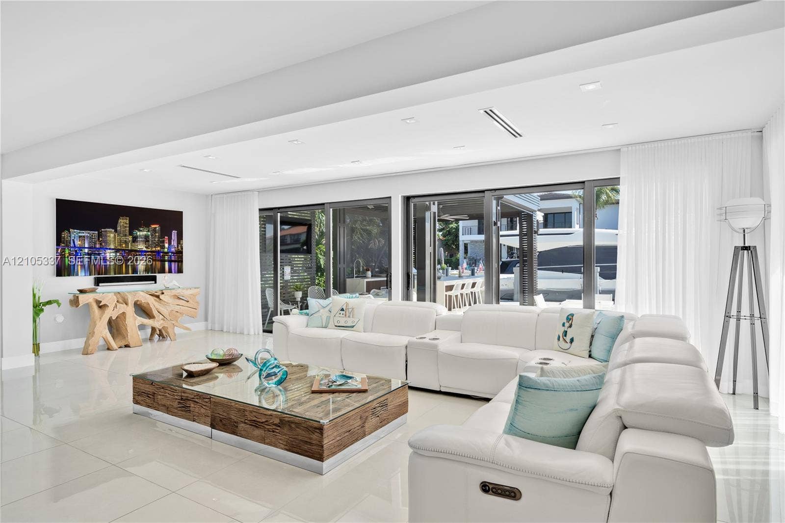 3322 NE 166th Street, North Miami Beach, FL 33160 Open-concept interior featuring large-format polished tile flooring, recessed ceiling lighting, and multi-panel glass sliding doors