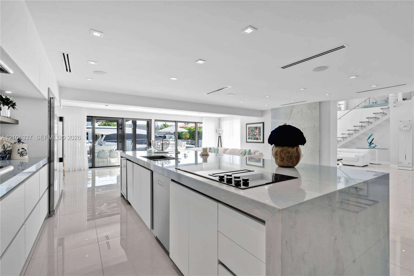 3322 NE 166th Street, North Miami Beach, FL 33160 Gourmet kitchen featuring a waterfall-edge center island, solid-surface countertops, flat-panel cabinetry, integrated appliances, and recessed ceiling lighting