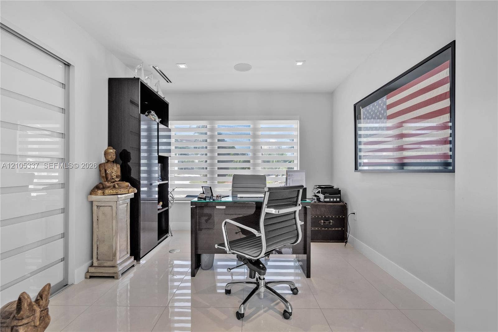 3322 NE 166th Street, North Miami Beach, FL 33160 Neutral-toned interior featuring large-format tile flooring, recessed ceiling lighting, horizontal blinds, and a built-in dark cabinetry unit
