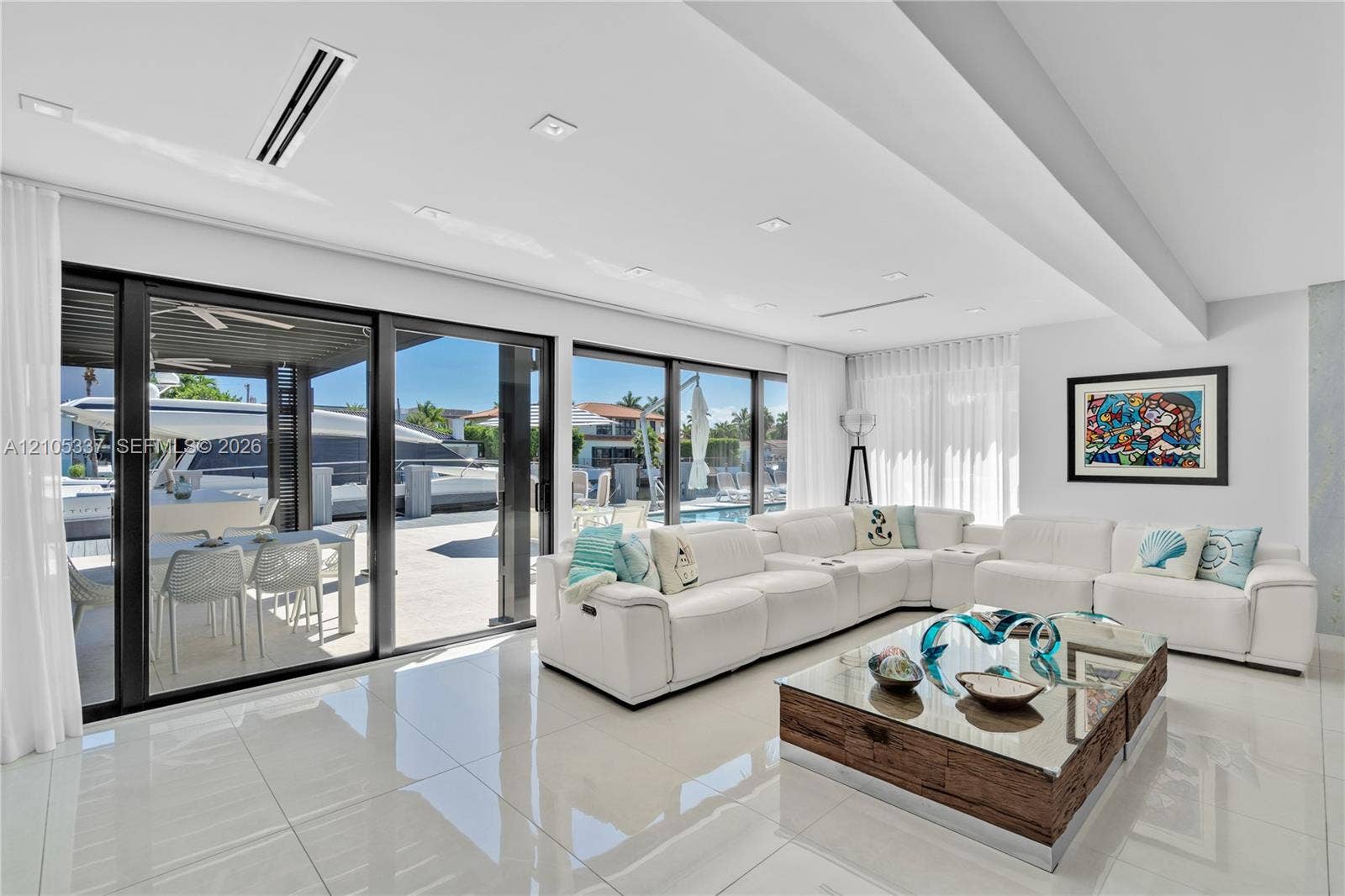 3322 NE 166th Street, North Miami Beach, FL 33160 Large-format porcelain tile flooring, recessed ceiling lighting, and expansive floor-to-ceiling sliding glass doors opening to a covered outdoor patio
