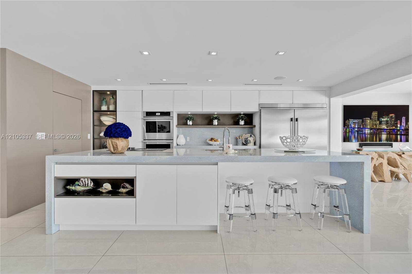 3322 NE 166th Street, North Miami Beach, FL 33160 Modern kitchen featuring a waterfall-edge island, flat-panel cabinetry, stainless steel built-in appliances, recessed lighting, and large-format tile flooring
