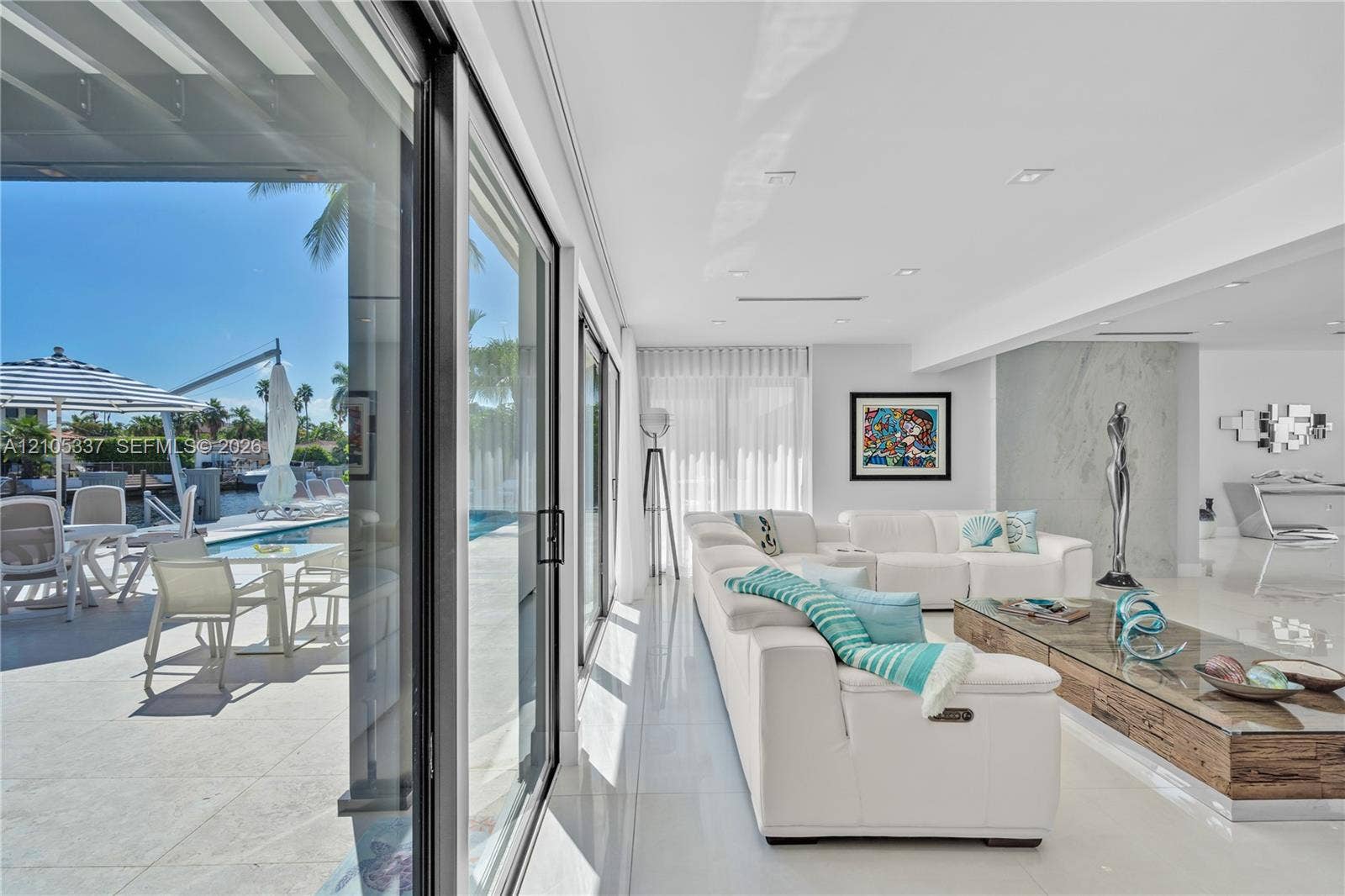 3322 NE 166th Street, North Miami Beach, FL 33160 Floor-to-ceiling sliding glass doors, polished tile flooring, recessed ceiling lighting, and a large-format feature wall with integrated stone-finish paneling