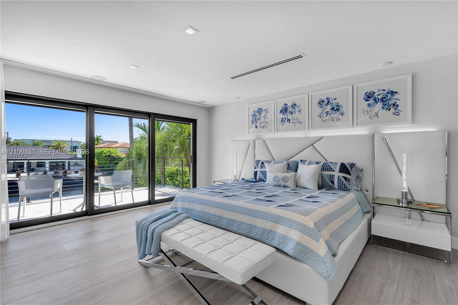 3322 NE 166th Street, North Miami Beach, FL 33160 Sliding glass wall panels opening to an outdoor balcony, wood-finish flooring, recessed ceiling lighting, and a built-in linear ceiling fixture