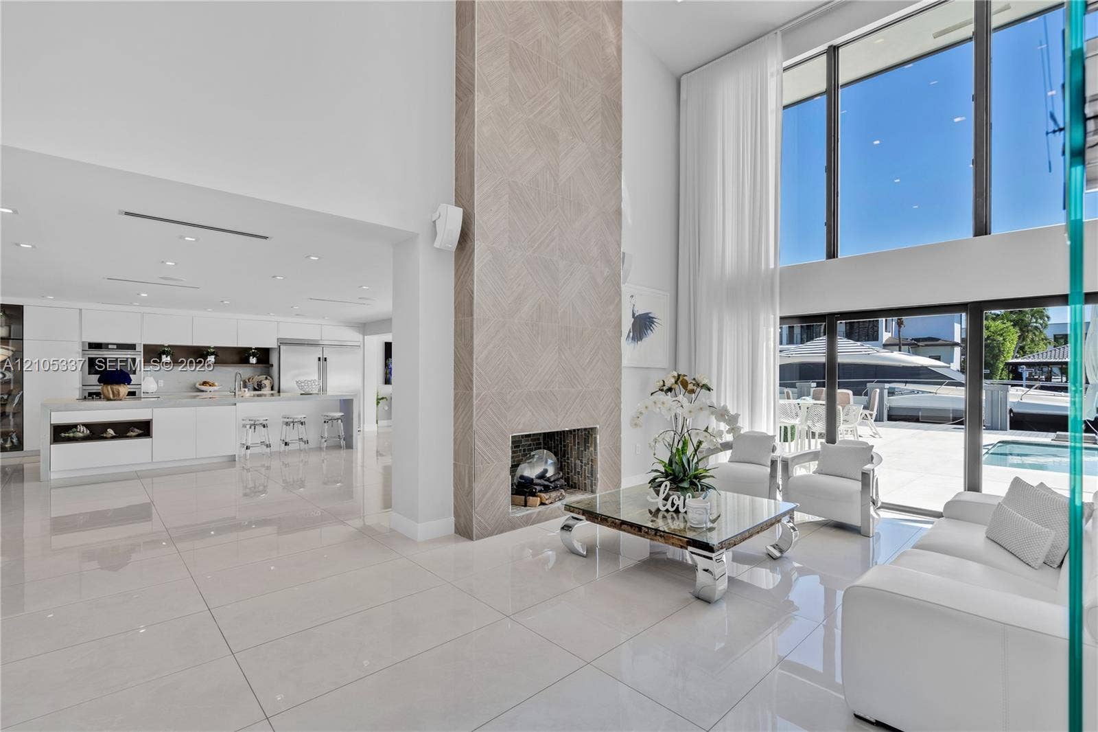 3322 NE 166th Street, North Miami Beach, FL 33160 Double-height living area featuring floor-to-ceiling windows, porcelain tile flooring, recessed lighting, and a floor-to-ceiling fireplace with geometric stone surround