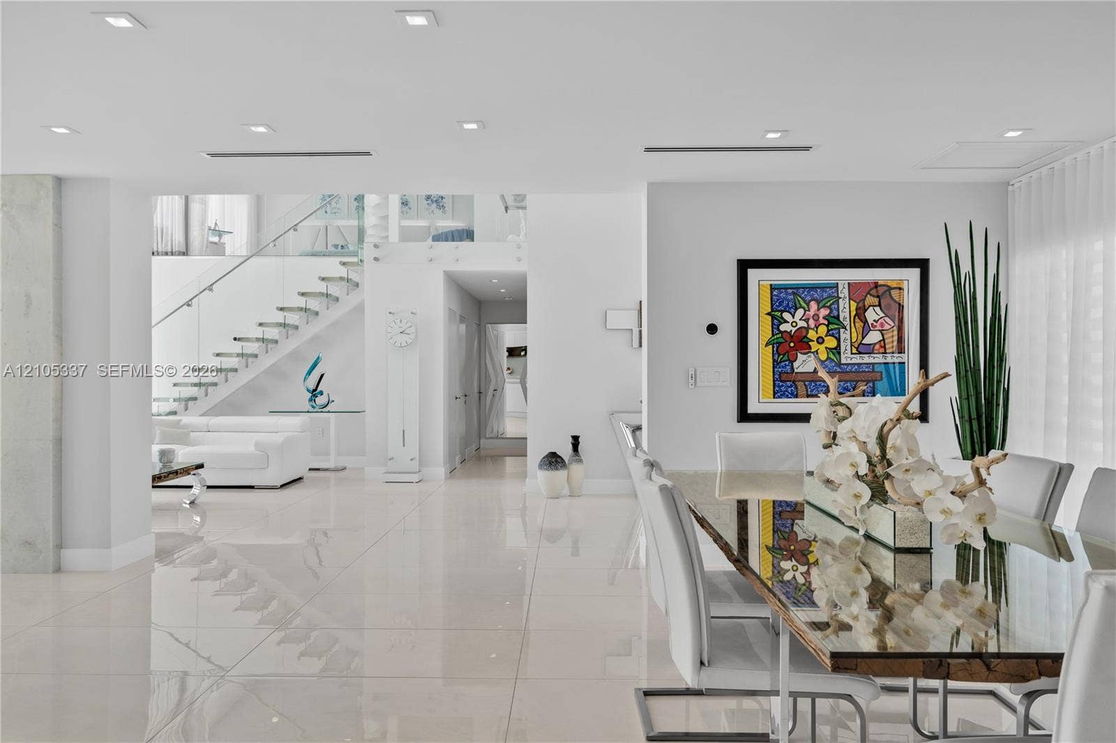 3322 NE 166th Street, North Miami Beach, FL 33160 Open-concept interior featuring large-format polished tile flooring, recessed ceiling lighting, and a staircase with glass railings and metal hardware