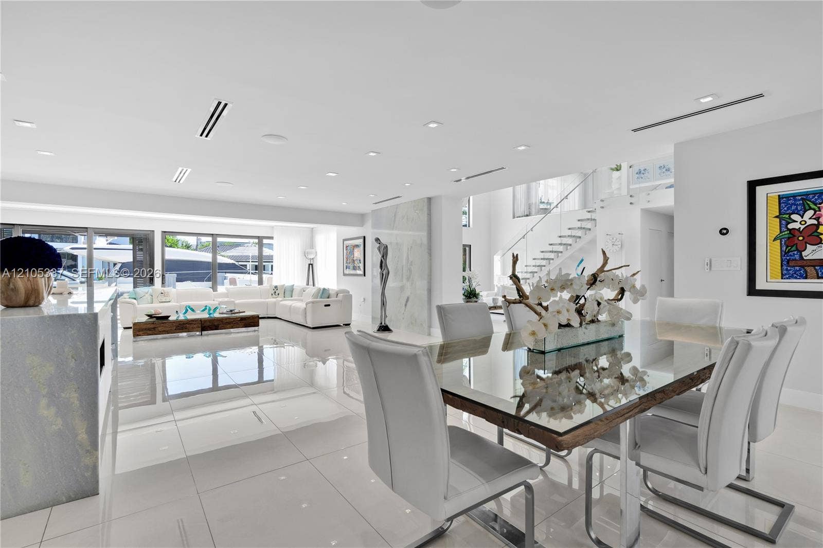 3322 NE 166th Street, North Miami Beach, FL 33160 Large-format porcelain tile flooring, recessed ceiling lighting, linear air diffusers, multi-panel sliding glass doors, and a staircase featuring glass panel railings