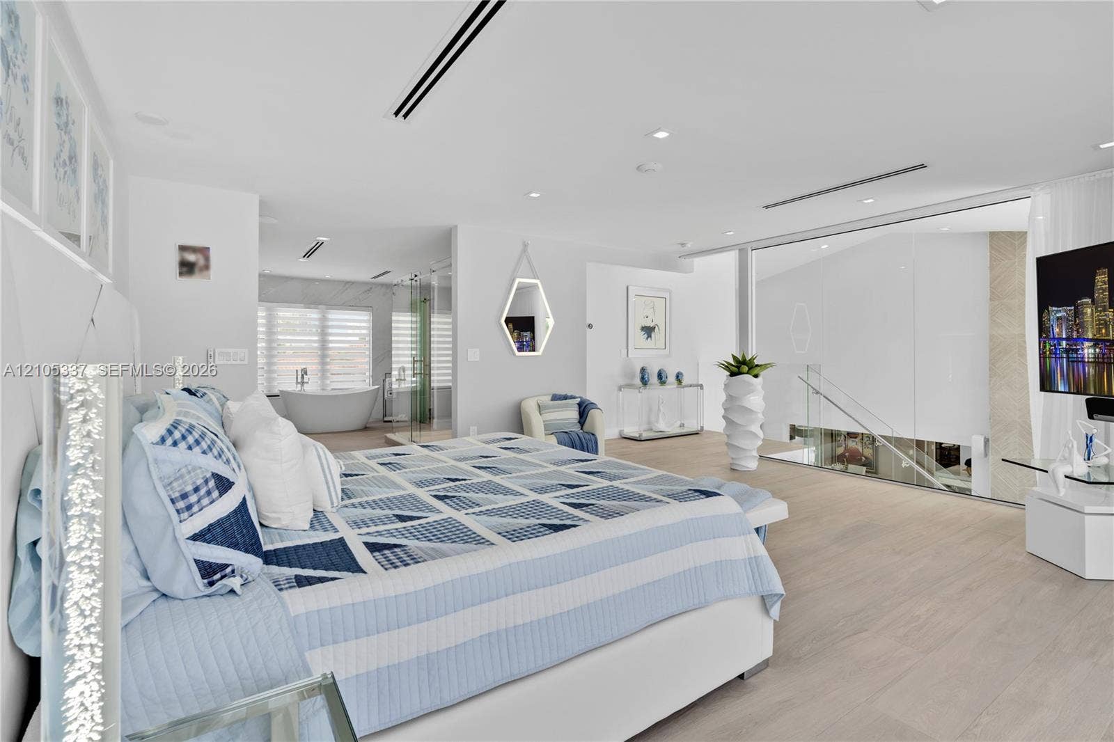 3322 NE 166th Street, North Miami Beach, FL 33160 Light-toned wood-finish flooring, recessed lighting, glass partition wall, and soaking tub with neutral stone-style tile