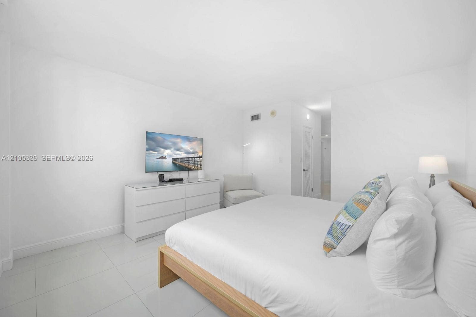 White walls, tile flooring, and a light wood-finish bed frame