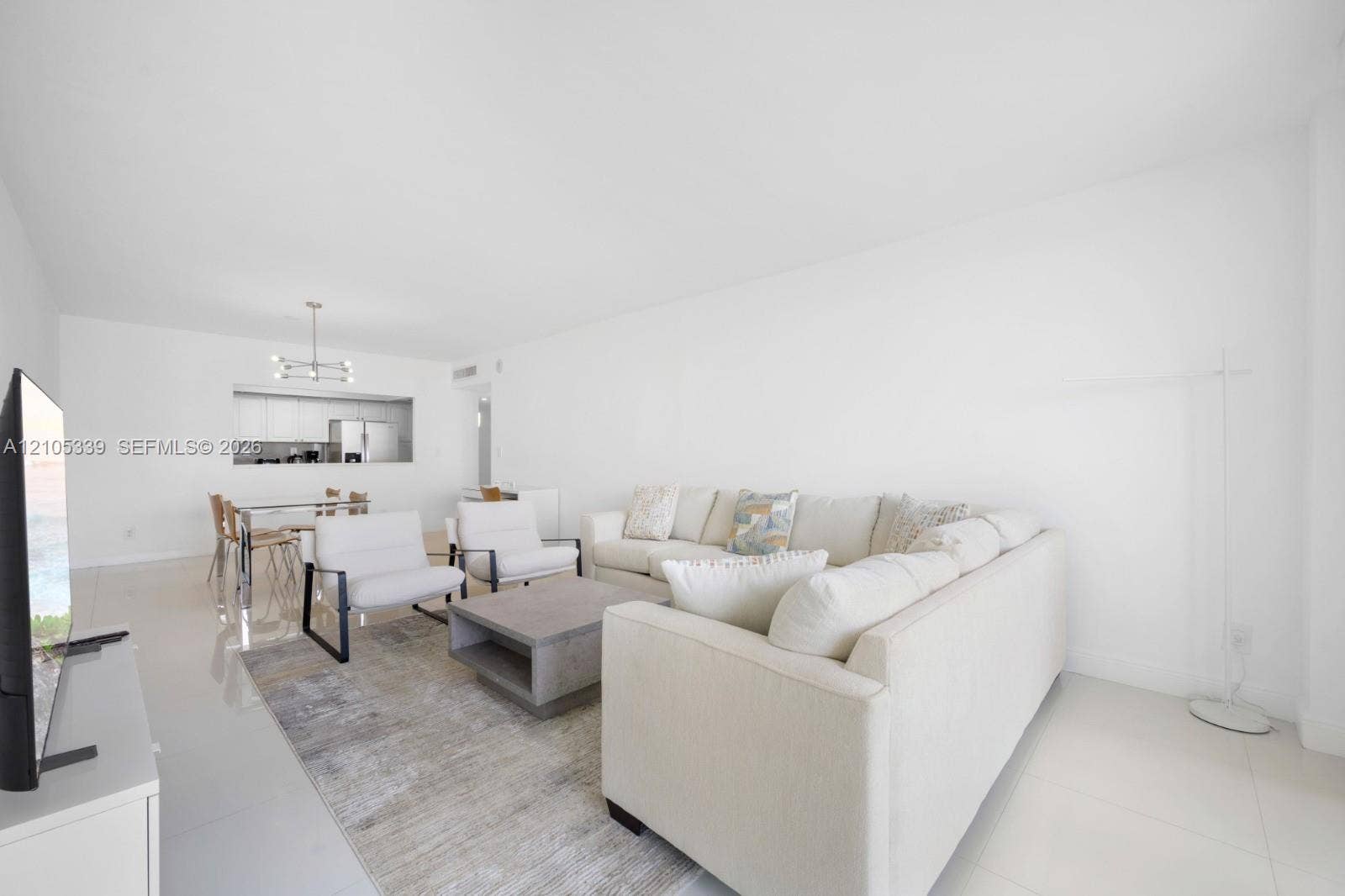 Open-concept living space with white walls and glossy tile flooring