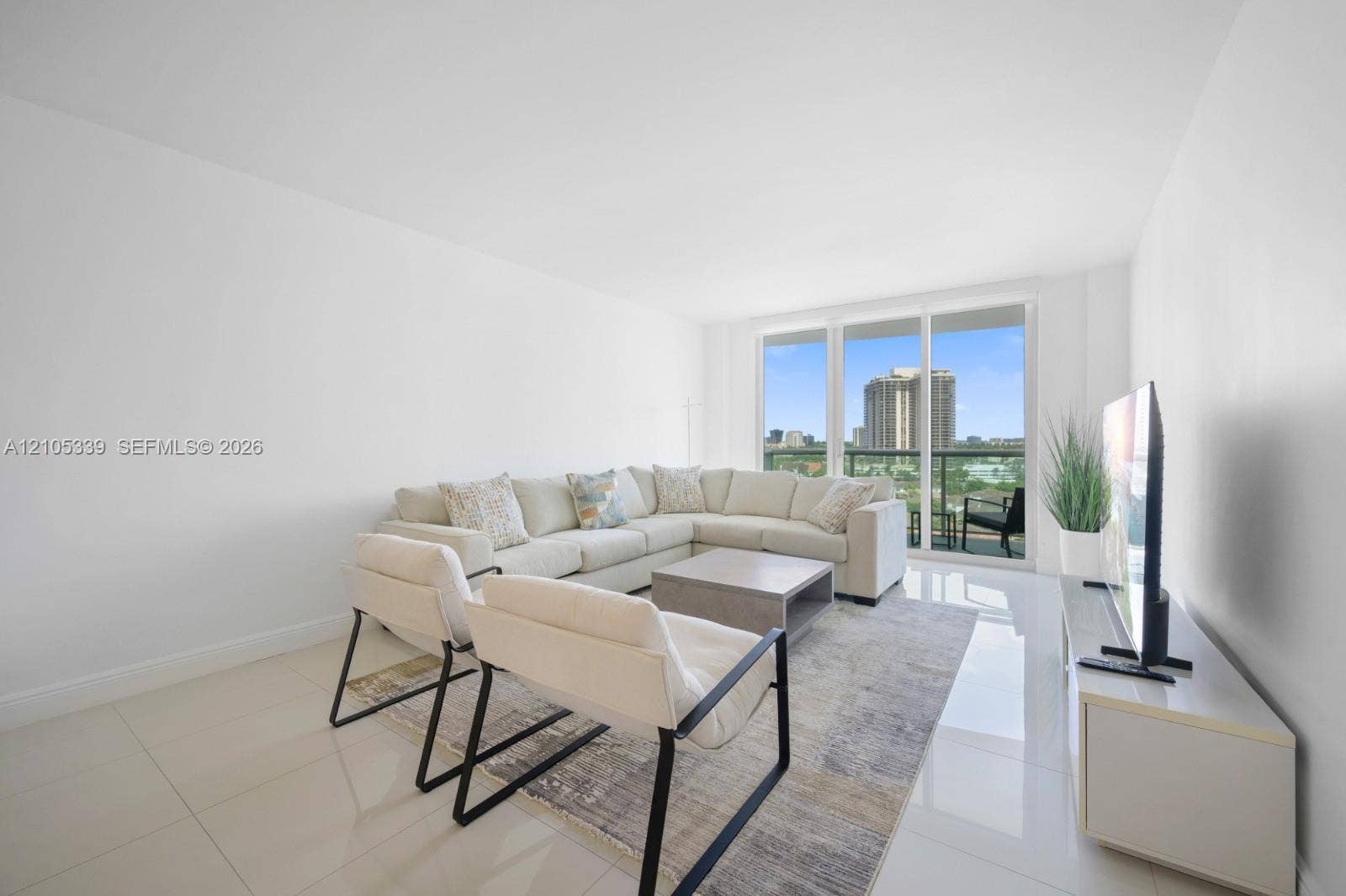 Expansive living area featuring light tile flooring and a sliding glass door to an outdoor balcony
