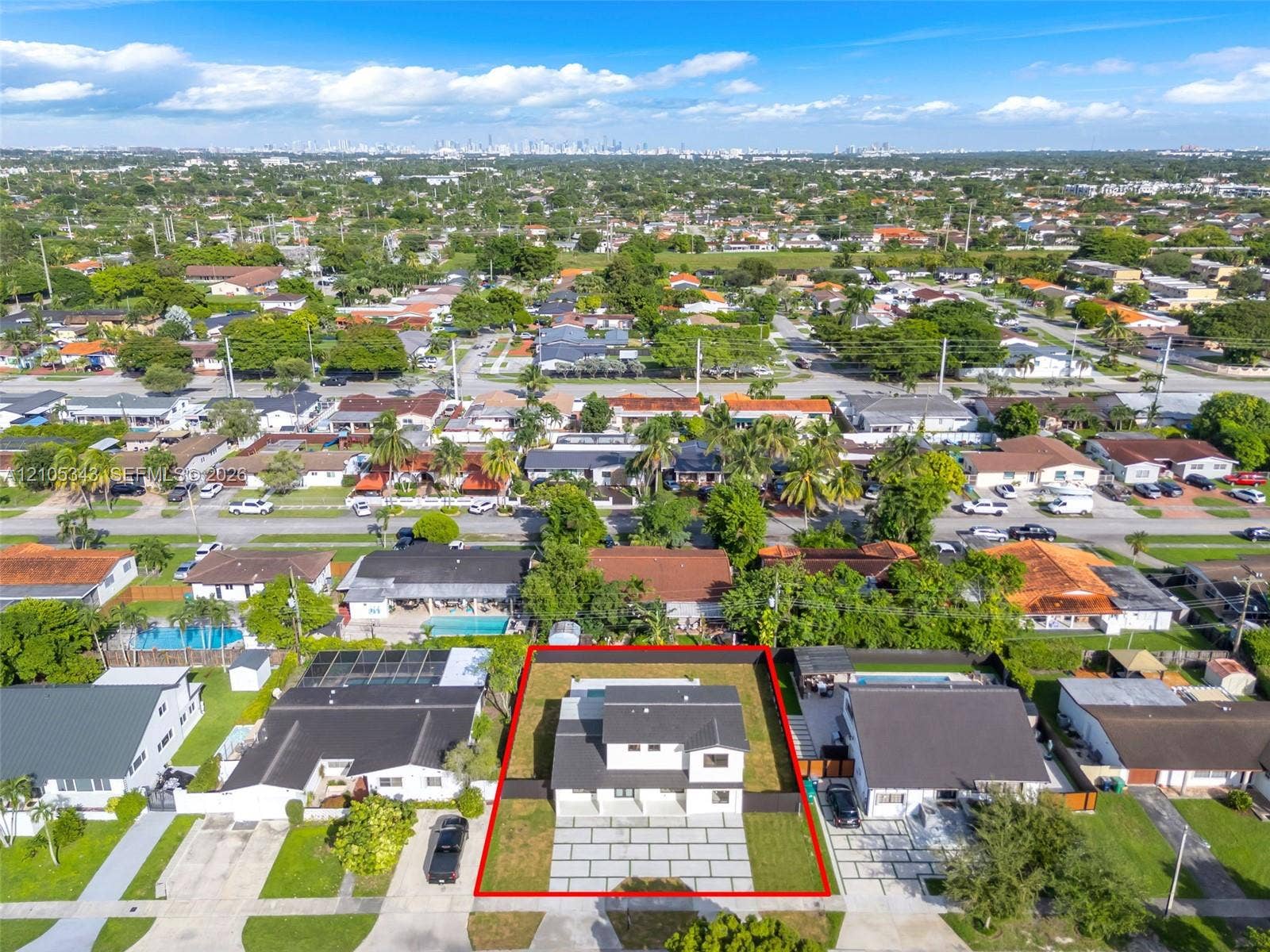 Two-story residence featuring a dark-toned pitched roof, clean white exterior finish, segmented paved driveway, and perimeter fencing