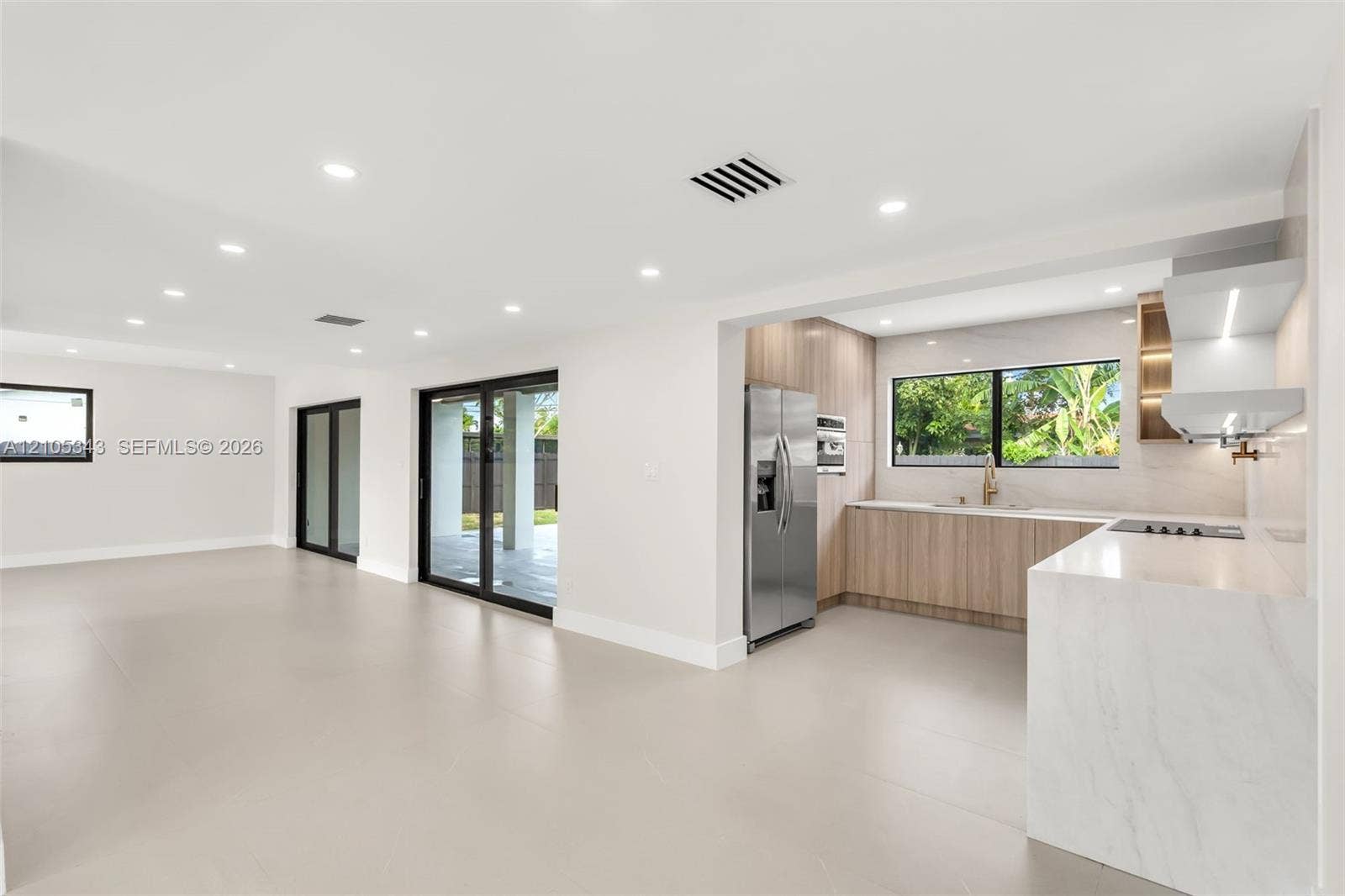 Open-concept interior featuring large-format tile flooring, recessed lighting, and sliding glass doors