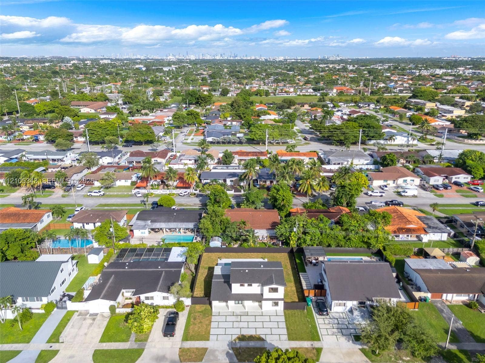Aerial perspective of a two-story residence featuring a paved driveway, dark-toned roofing, and a fenced backyard