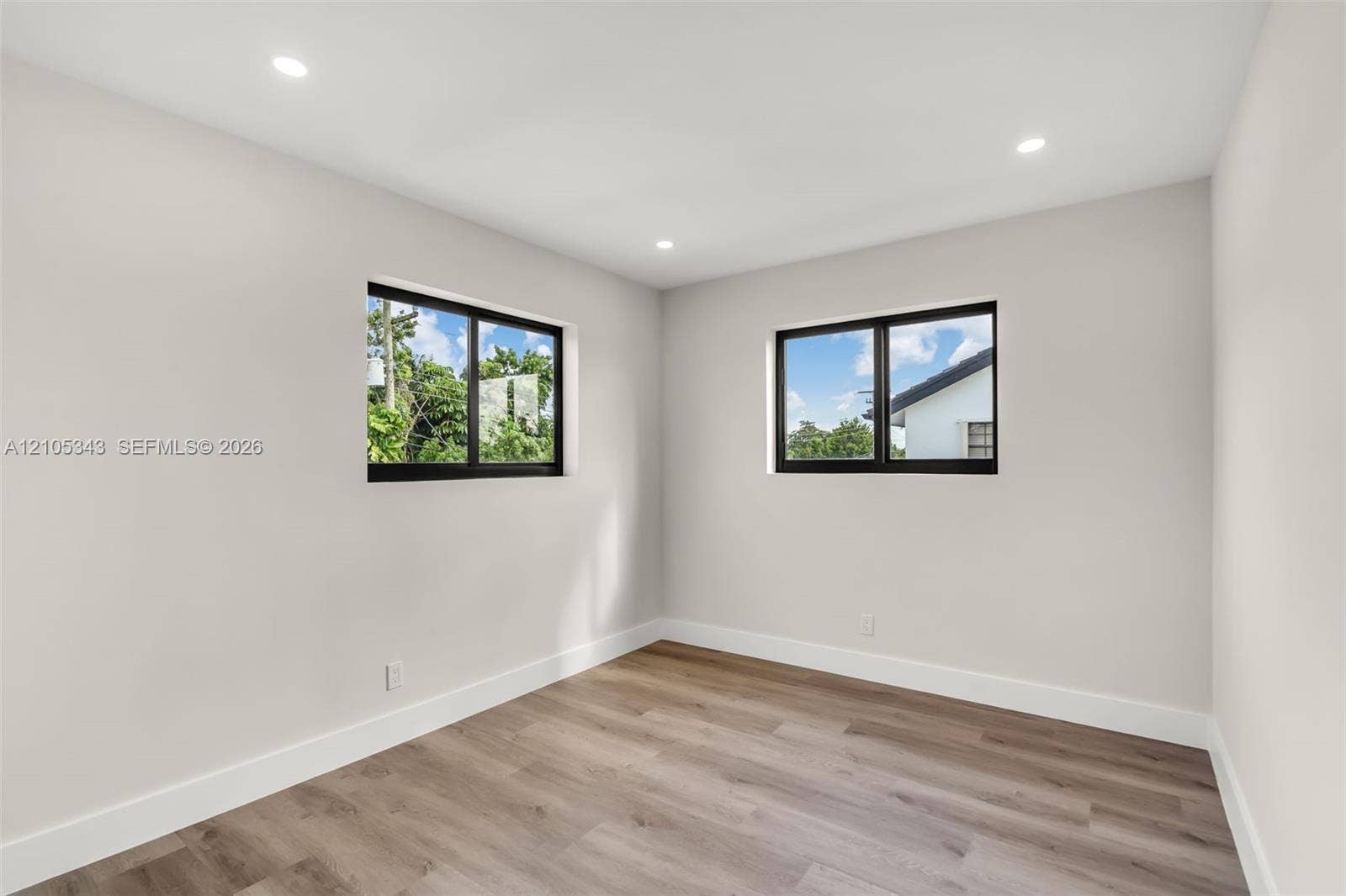 Interior space featuring wood-finish flooring, neutral wall tones, recessed lighting, and dual windows with black frames