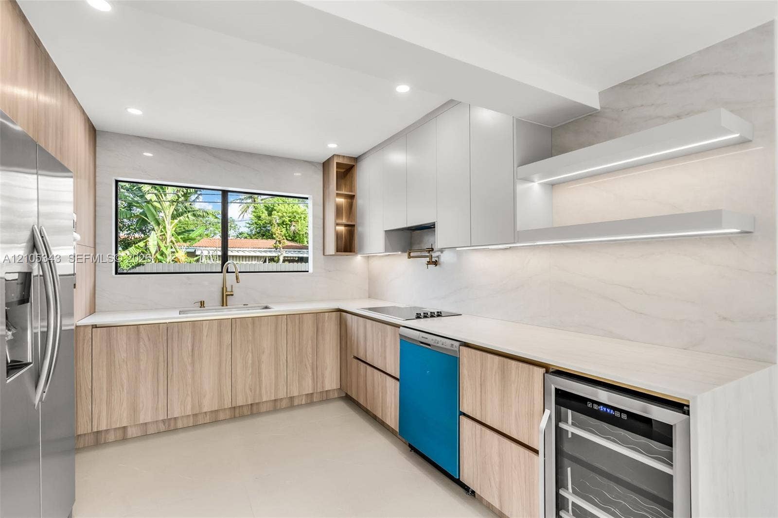 Kitchen featuring light wood-finish cabinetry, solid-surface countertops, full-height stone-look backsplash, built-in under-counter beverage refrigerator, and integrated LED shelving