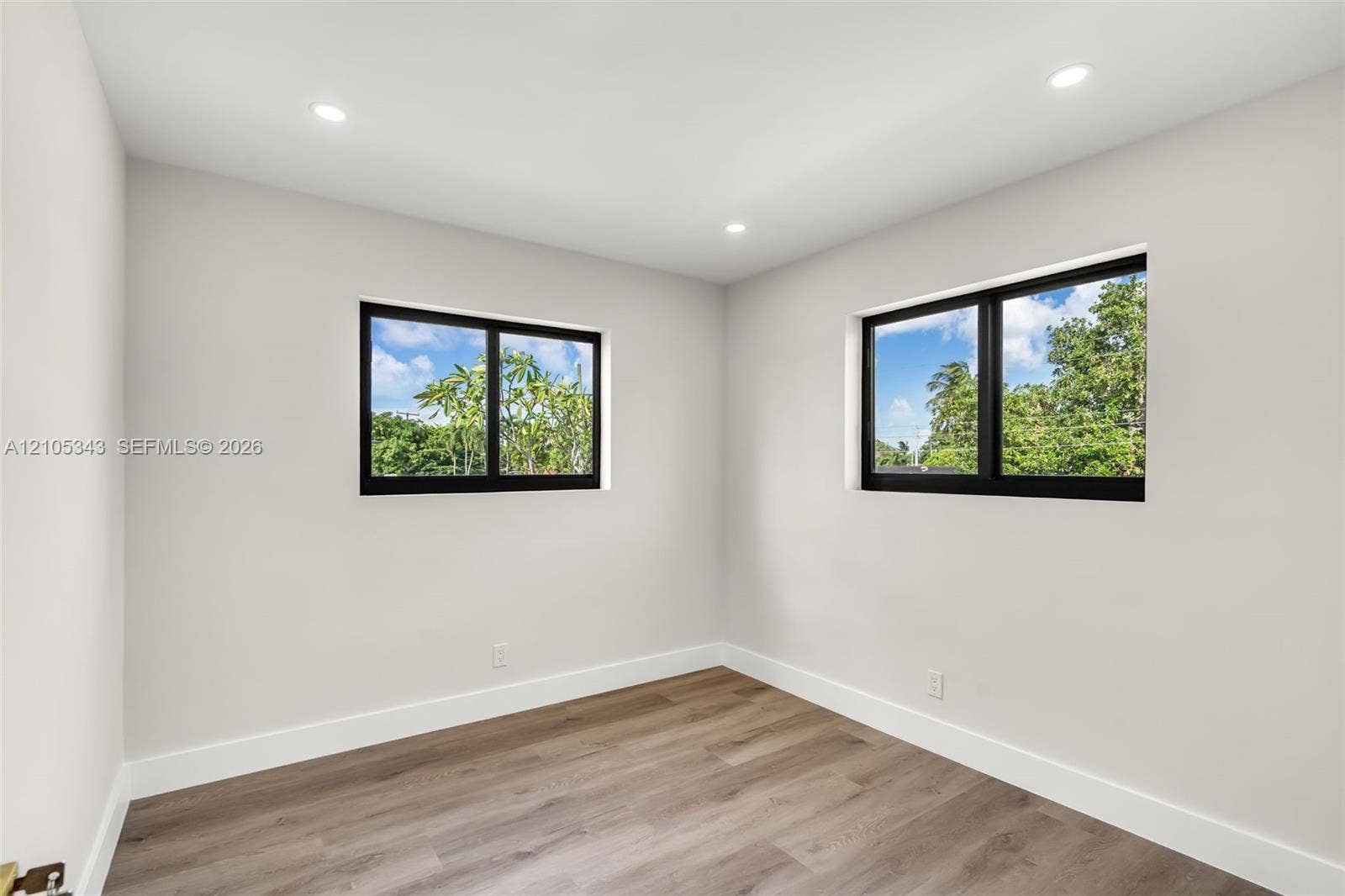 Neutral wall palette featuring wood-finish flooring, recessed lighting, and dual windows with black frames