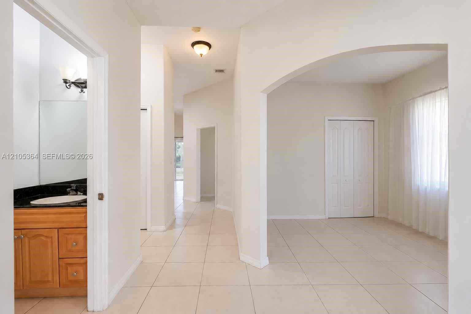 Tiled flooring throughout, an arched entryway, bifold closet doors, and recessed lighting