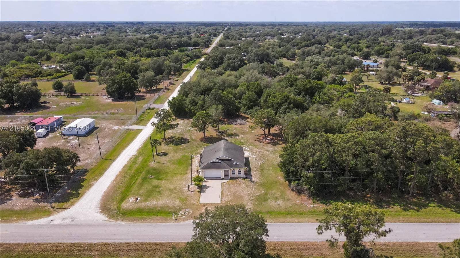 Single-story residence with an attached garage, set on a manicured lawn with mature trees, and a paved driveway