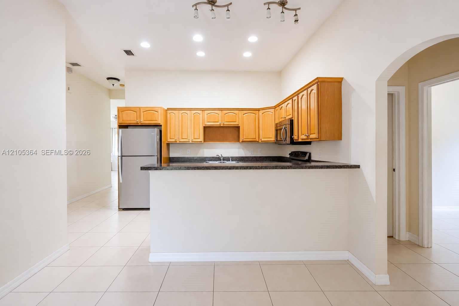 Kitchen featuring a breakfast bar, stainless steel appliances, wood cabinetry, and a dark countertop