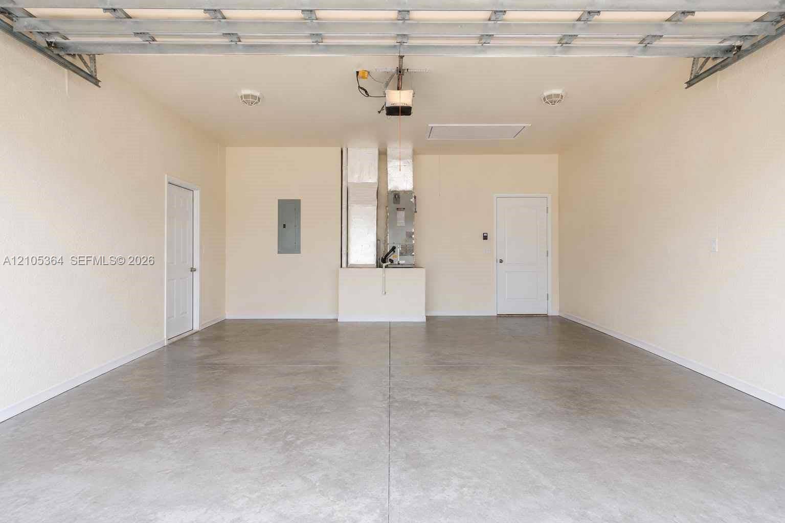 Concrete flooring with light-toned walls, featuring a side access door and an additional door