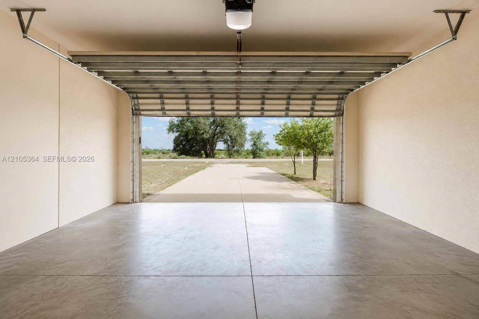 Expansive garage with a concrete floor, light-toned walls, and an automatic overhead door