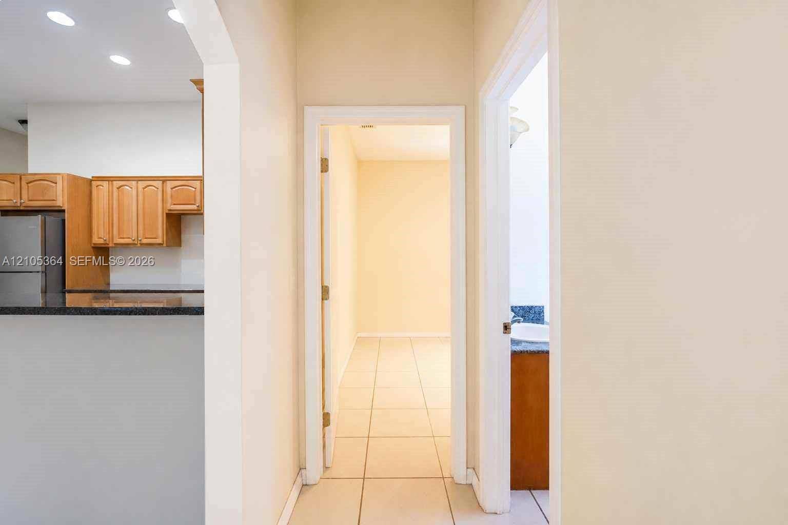 Arched doorway with recessed lighting, tile flooring, wood cabinetry, and stainless steel appliances