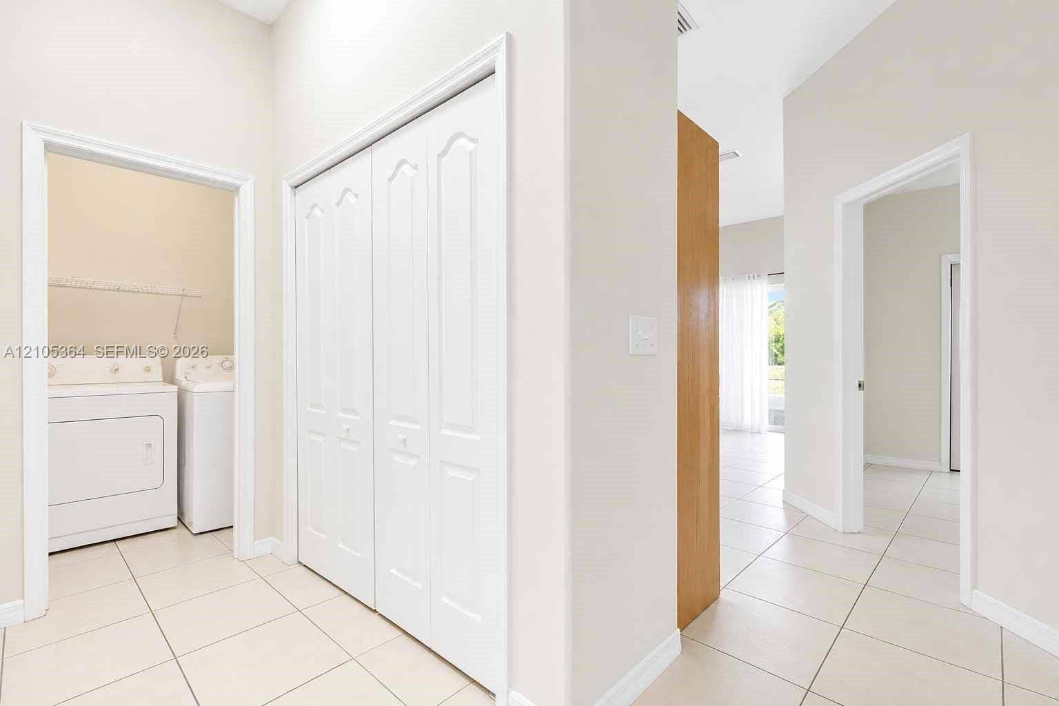 Hallway featuring white bi-fold closet doors and neutral tile flooring