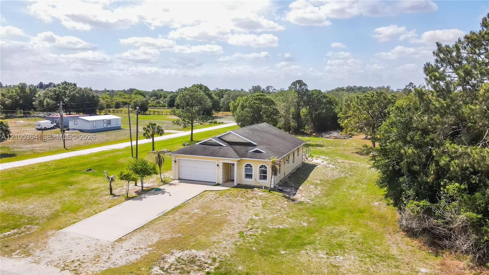 Single-story residence with a paved driveway, attached garage, and mature trees