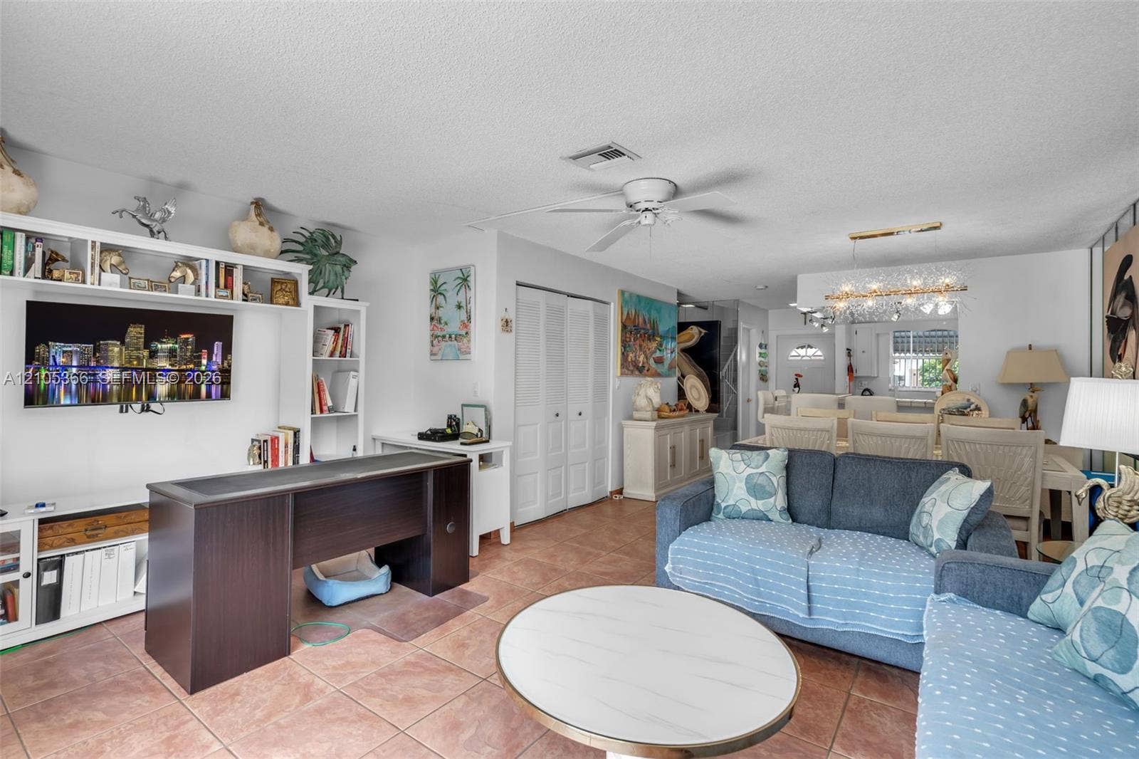 Open-concept living area featuring tile flooring, a ceiling fan, and built-in shelving