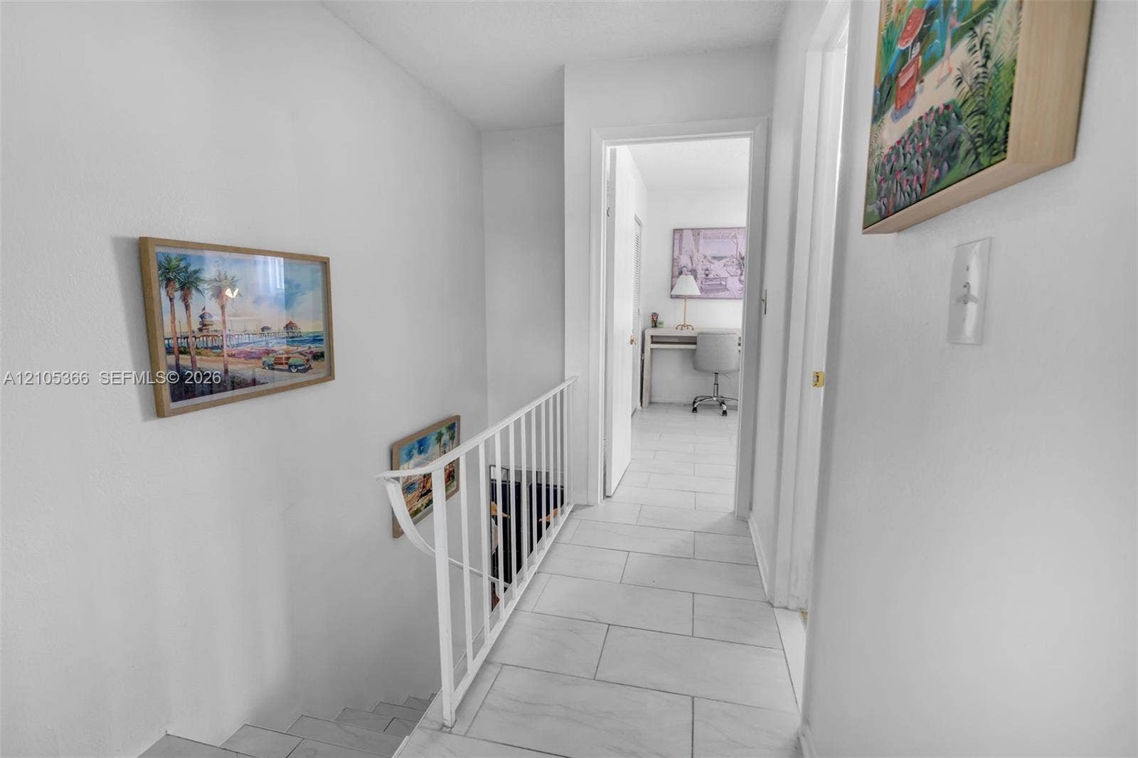 Hallway with tiled flooring and white painted walls, featuring a white metal stair railing