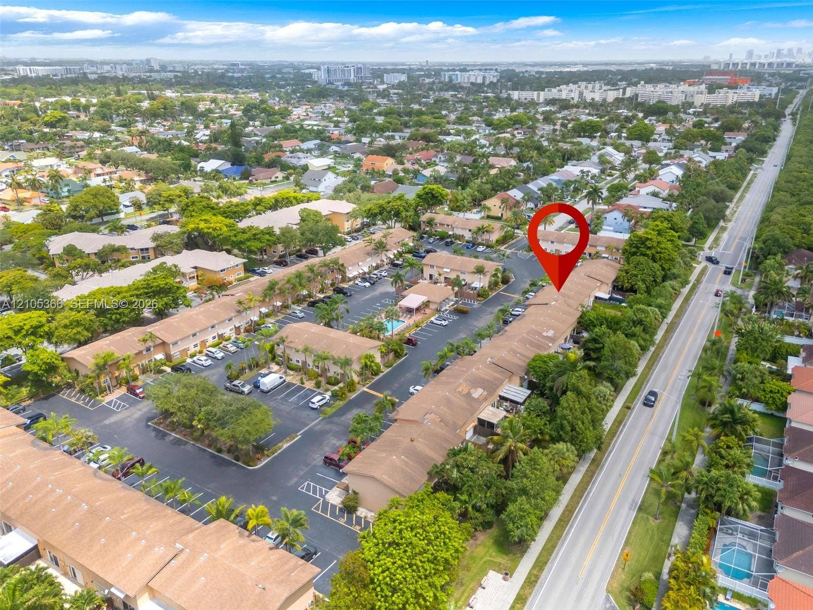 Aerial perspective showcasing multiple residential buildings, paved parking areas, and mature landscaping