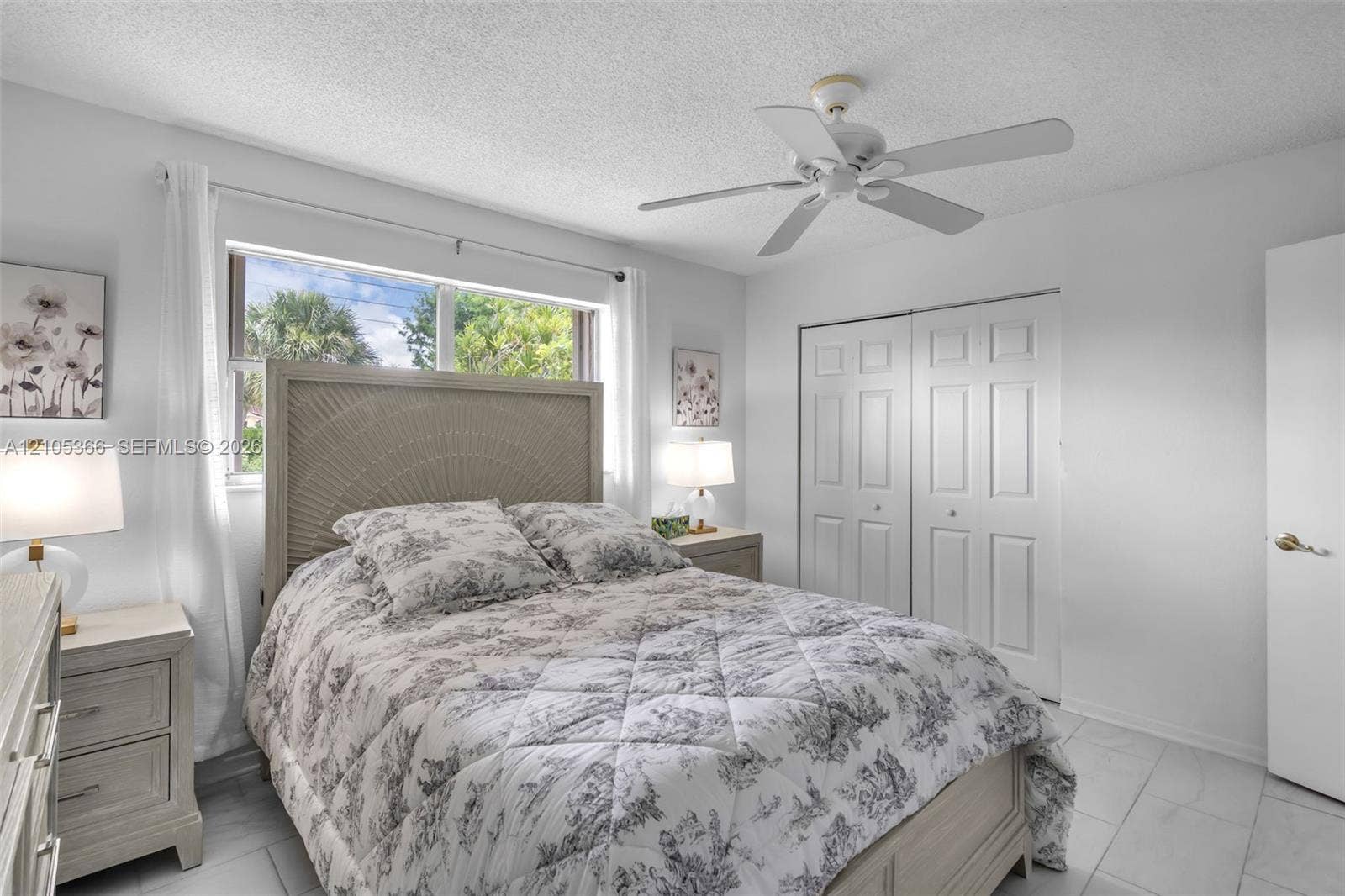 White tile flooring, a window with natural light, a ceiling fan, and bi-fold closet doors