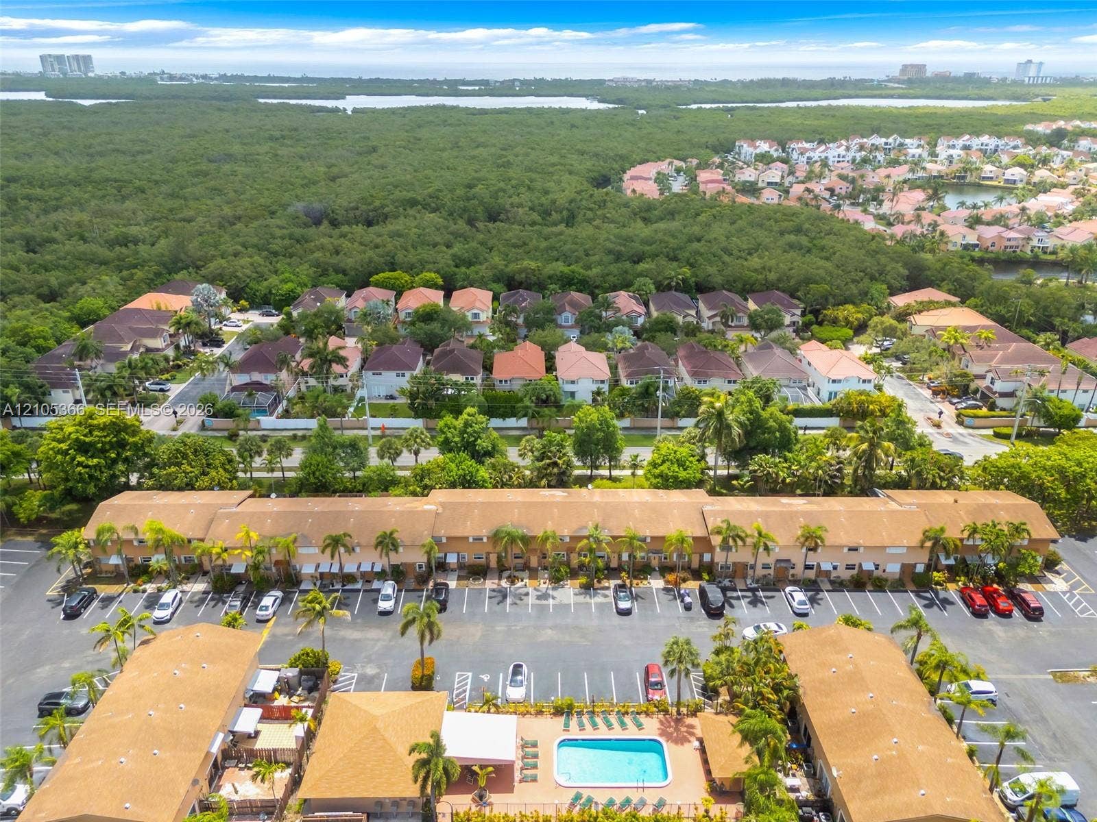 Community featuring a central swimming pool, paved parking areas, and mature palm trees