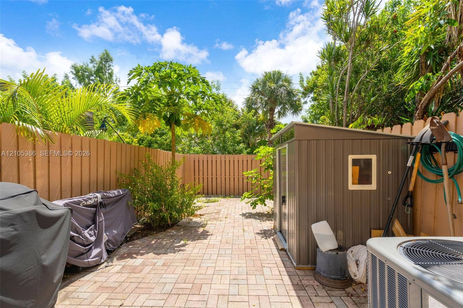 Paver patio with a wood privacy fence and mature landscaping