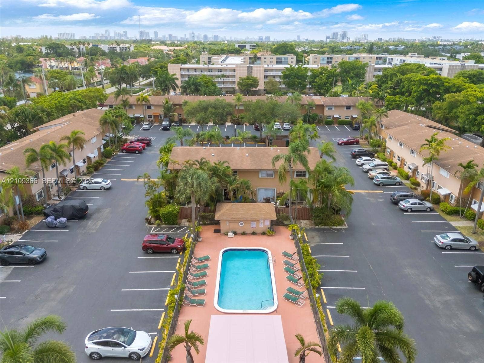 Community pool and expansive parking areas surrounded by mature palm trees