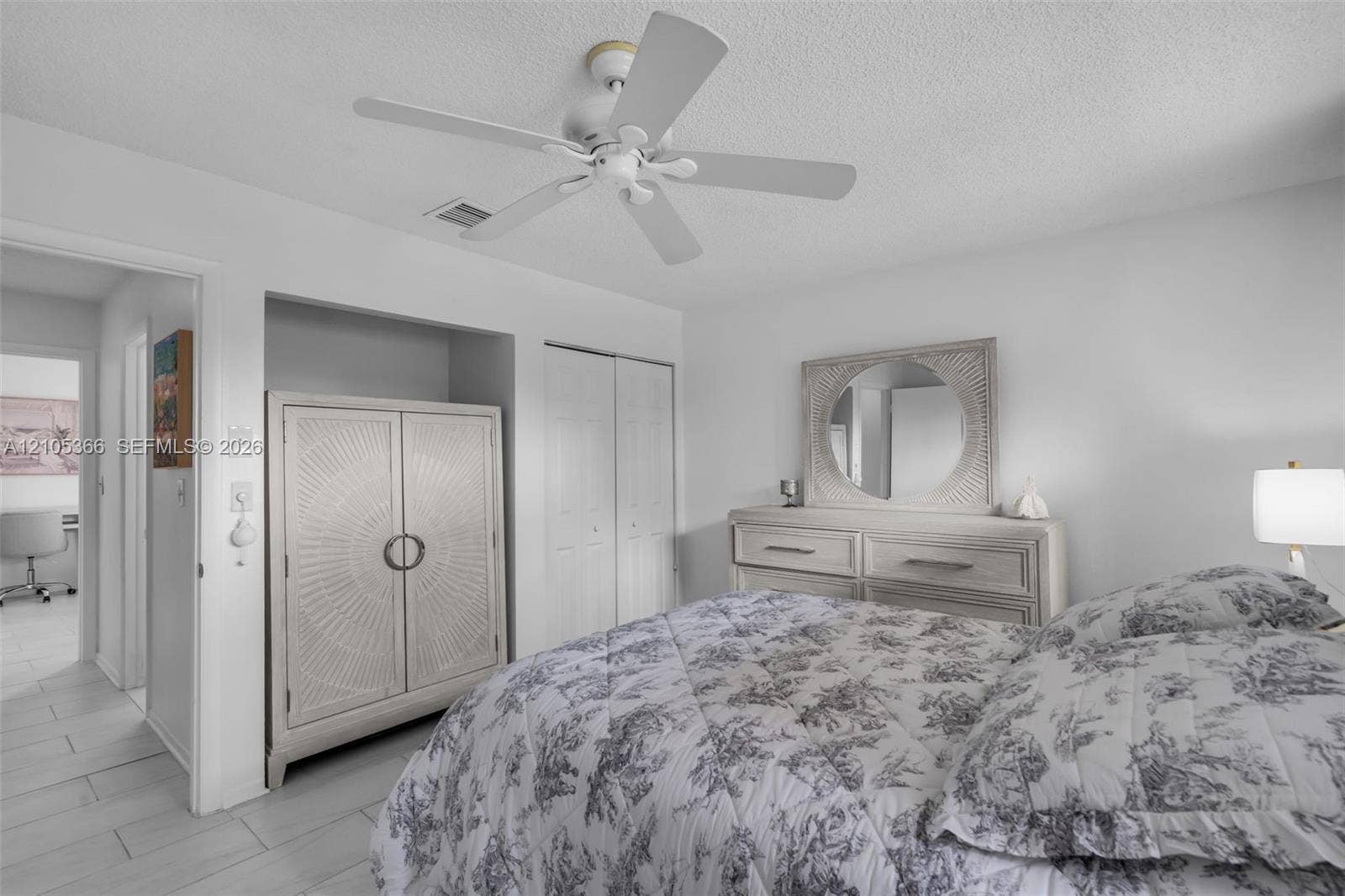 White ceiling fan, recessed wall niche, bifold closet doors, and wood-finish flooring