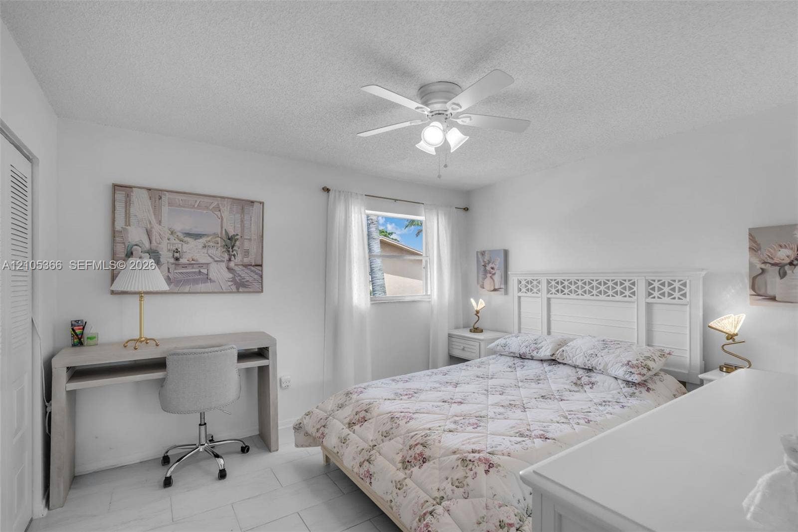 White ceiling fan with integrated lighting, window with white curtains, white walls, and white tile flooring