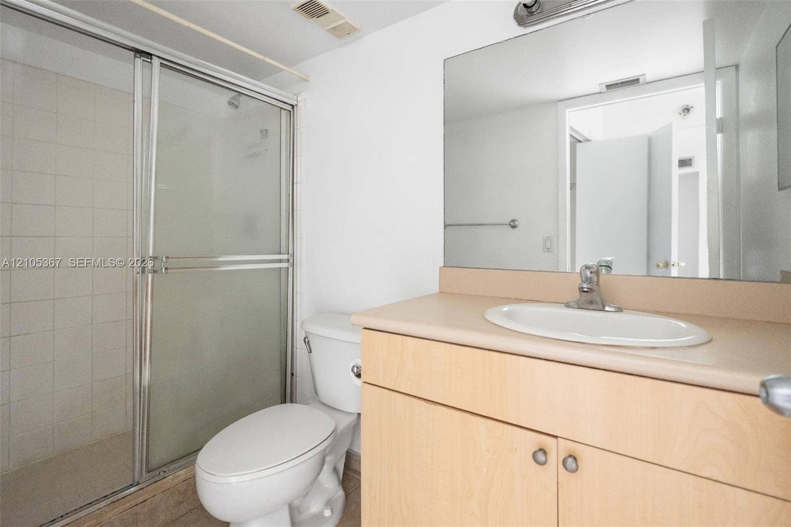 9066 W Atlantic Boulevard, #412, Coral Springs, FL 33071 Bathroom featuring a shower with a sliding glass door, a light-finish wood cabinet vanity, an integrated countertop with an oval basin, and a wall-mounted mirror
