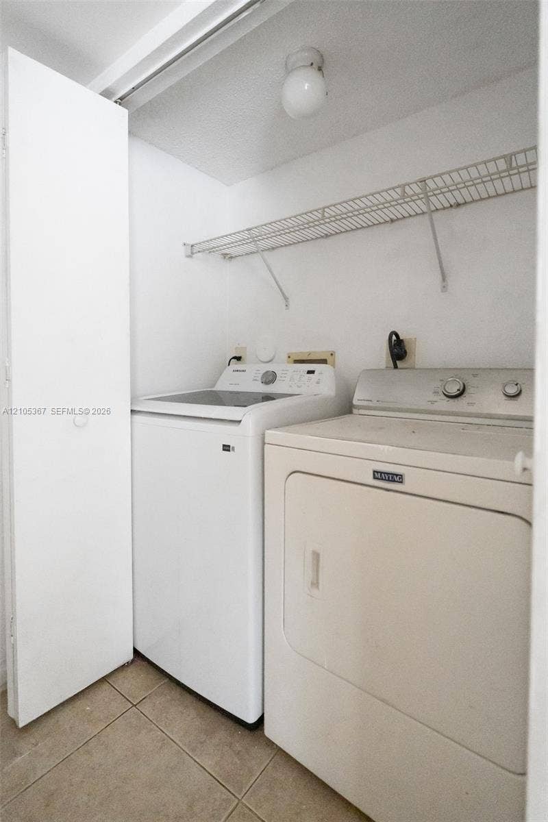 9066 W Atlantic Boulevard, #412, Coral Springs, FL 33071 Utility area featuring ceramic tile flooring, built-in wire shelving, and a ceiling-mounted globe light fixture
