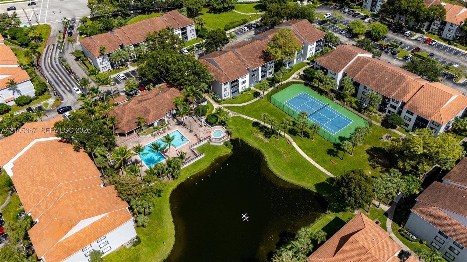 9066 W Atlantic Boulevard, #412, Coral Springs, FL 33071 Aerial perspective of the community featuring a central pond, tennis court, swimming pool with spa, and manicured landscaping