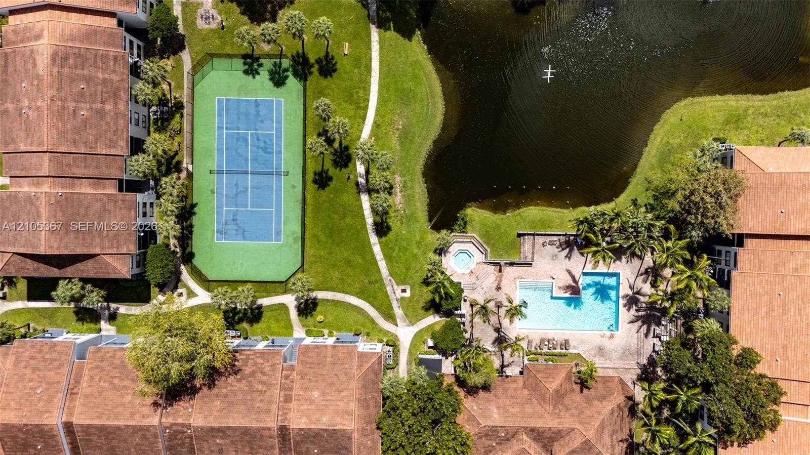 9066 W Atlantic Boulevard, #412, Coral Springs, FL 33071 Aerial perspective of a multi-unit complex featuring a fenced tennis court, swimming pool, spa, and a natural pond