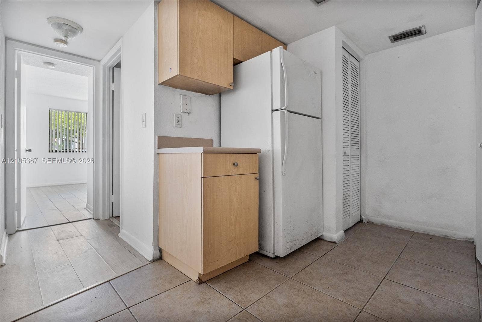 9066 W Atlantic Boulevard, #412, Coral Springs, FL 33071 Kitchen area featuring light-finish cabinetry, a built-in refrigerator, tile flooring, and louvered closet doors