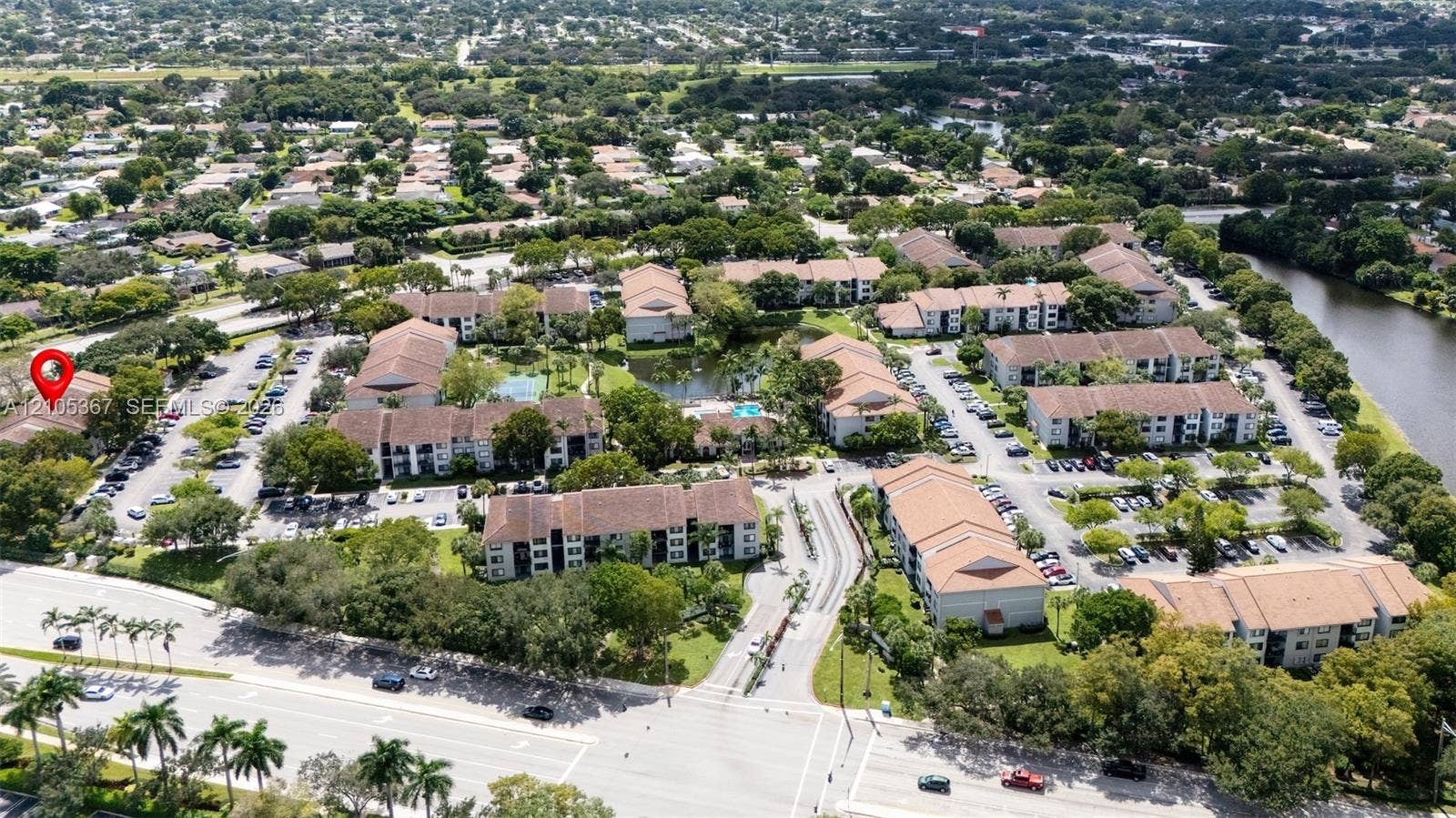 9066 W Atlantic Boulevard, #412, Coral Springs, FL 33071 Aerial perspective of a multi-building residential community featuring tile roofs, paved parking lots, landscaped grounds, and proximity to a canal