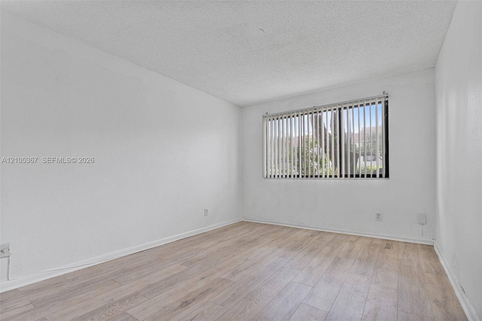 9066 W Atlantic Boulevard, #412, Coral Springs, FL 33071 Interior space featuring light-toned wood-finish flooring, white walls, and a window with vertical blinds
