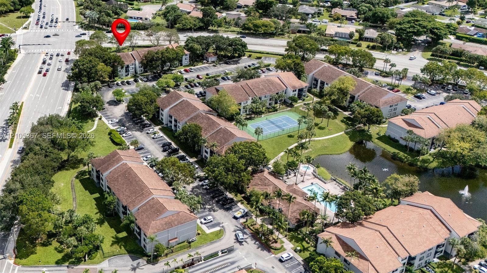 9066 W Atlantic Boulevard, #412, Coral Springs, FL 33071 Aerial perspective of multi-unit complex featuring tile roof architecture, communal tennis court, swimming pool, and on-site water feature
