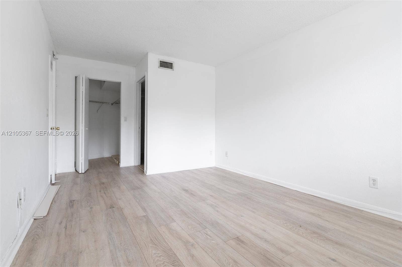 9066 W Atlantic Boulevard, #412, Coral Springs, FL 33071 Neutral-toned wood-finish flooring, white walls, and a closet with bifold doors