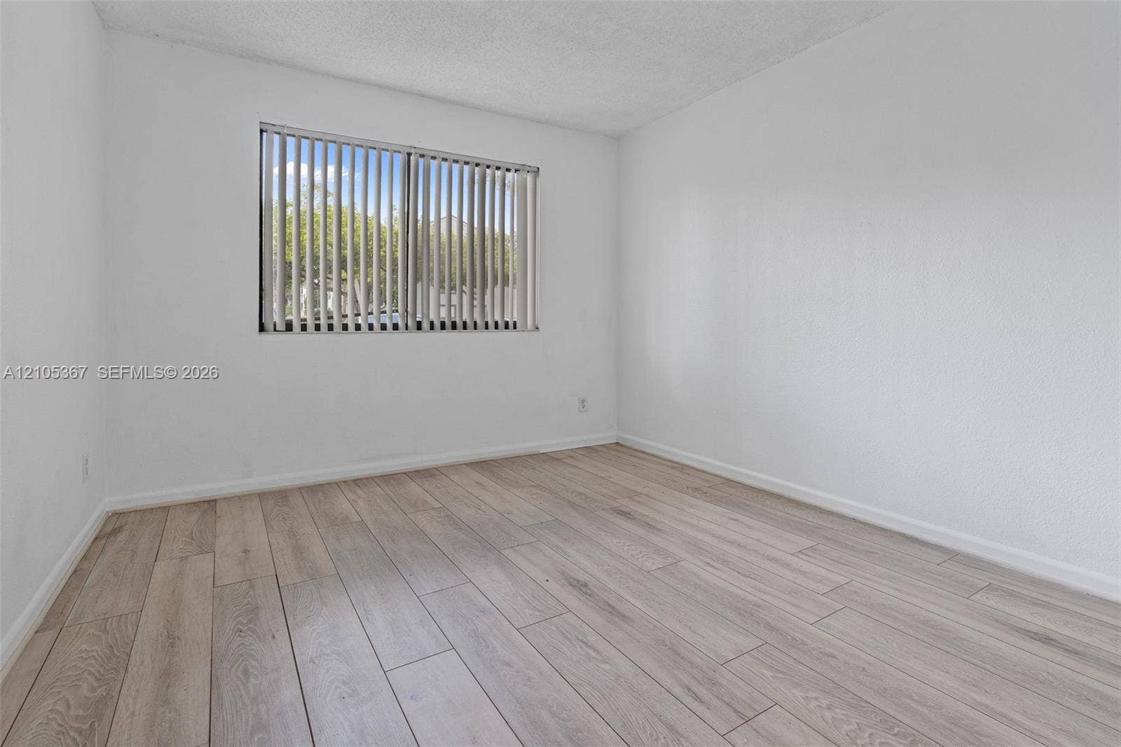 9066 W Atlantic Boulevard, #412, Coral Springs, FL 33071 Interior space featuring neutral wall tones, wood-finish flooring, and a window with vertical blinds