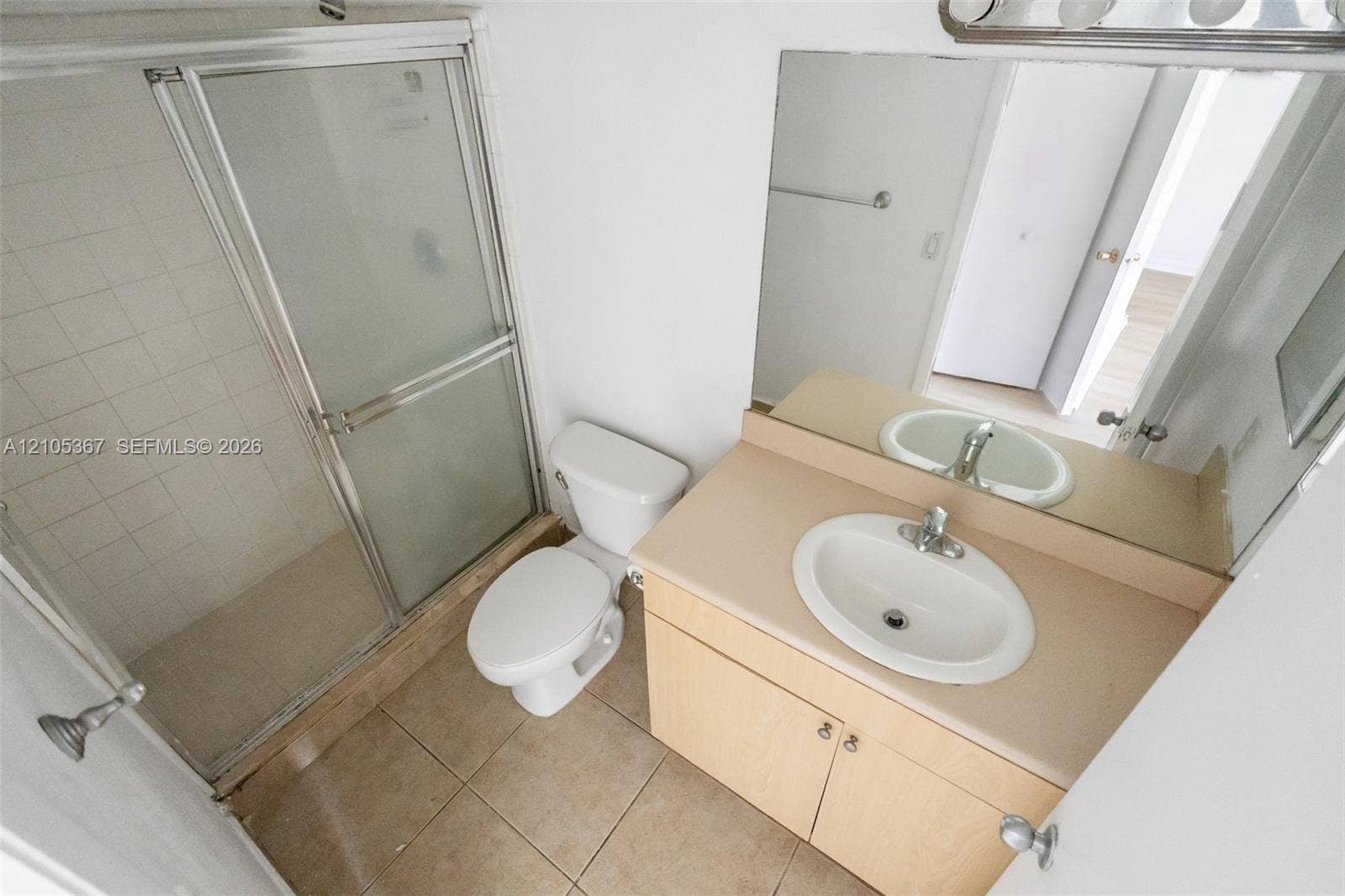 9066 W Atlantic Boulevard, #412, Coral Springs, FL 33071 Bathroom featuring a vanity with an integrated basin, a large wall-mounted mirror, ceramic tile flooring, and a glass-enclosed shower stall with tiled surround