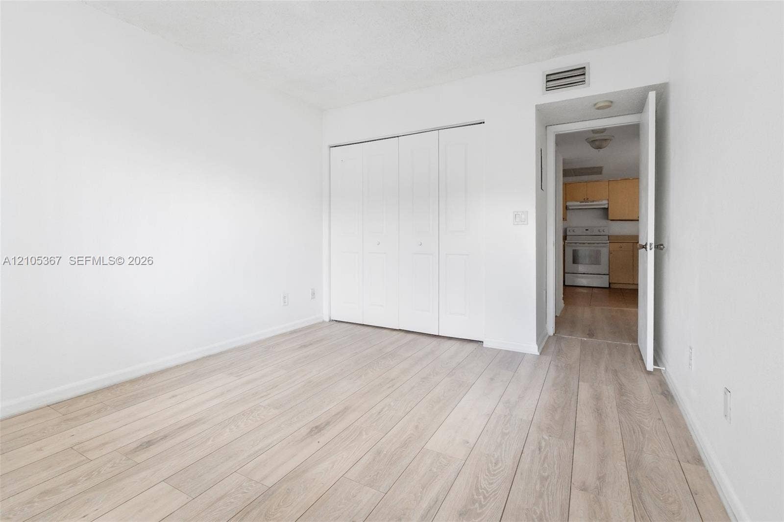 9066 W Atlantic Boulevard, #412, Coral Springs, FL 33071 Interior space featuring wood-finish flooring, white walls, and a large reach-in closet with white paneled bi-fold doors