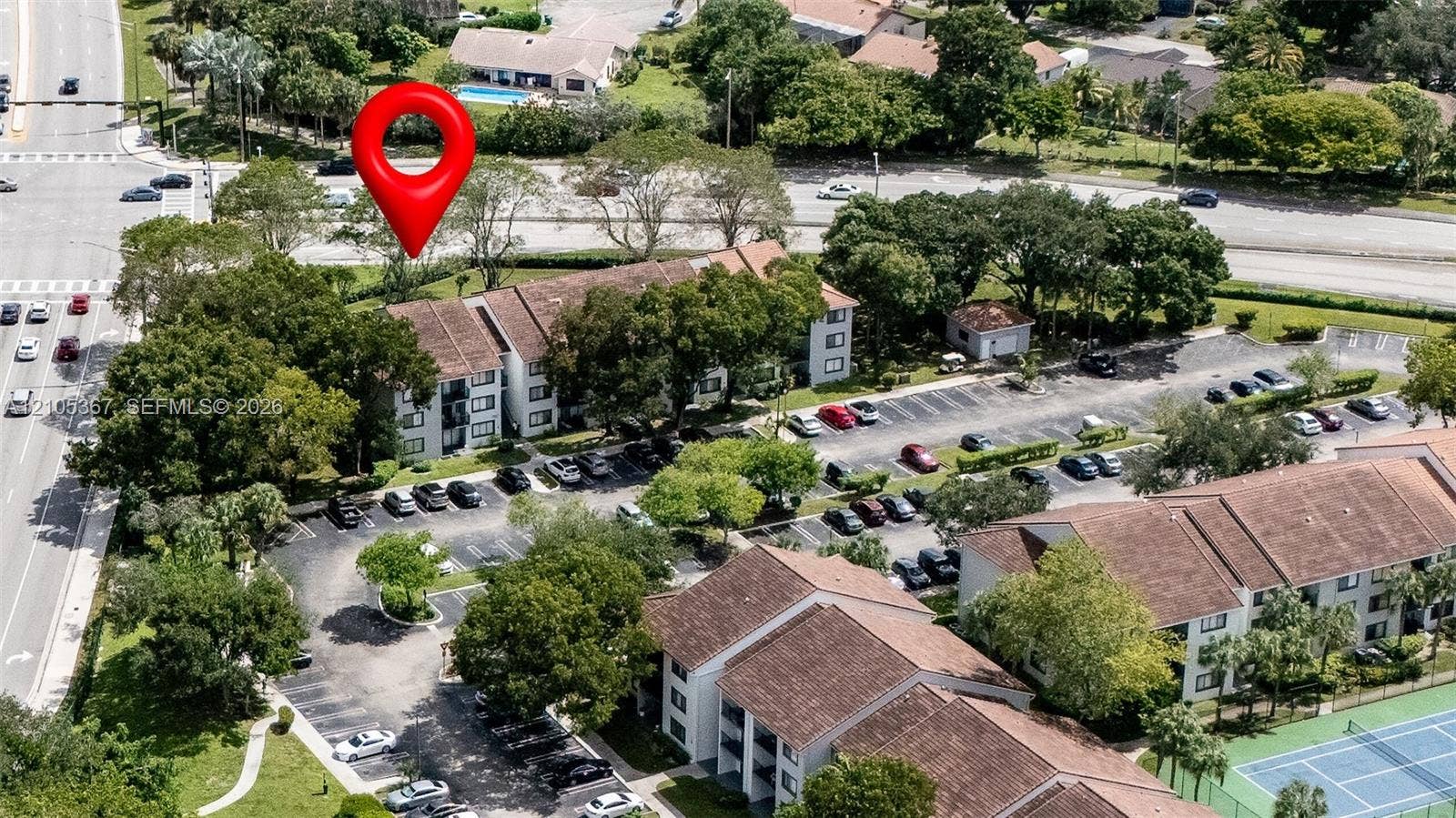 9066 W Atlantic Boulevard, #412, Coral Springs, FL 33071 Aerial perspective of a multi-story residential building featuring a tile roof, paved parking areas, and a hard-court surface